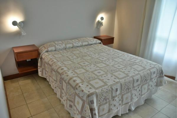 1 dormitorio con 1 cama con 2 mesitas de noche y 2 mesas en Cabañas Cambados en Villa Gesell