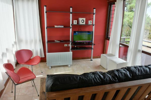 sala de estar con sofá y TV en Cabañas Cambados en Villa Gesell
