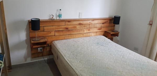 1 cama en un dormitorio con cabecero de madera en Casa costa chica en Las Toninas