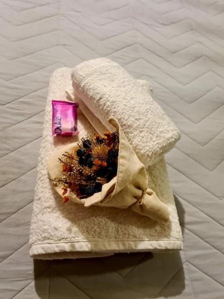 Una toalla en una cama con una vela rosa y flores en Altos Dean Funes en Salta