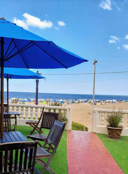 un patio con sillas y una sombrilla azul y la playa en Los Tritones Apart Hotel en Villa Gesell