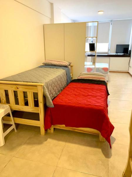 1 dormitorio con 2 camas y manta roja en Departamento Independencia en Buenos Aires
