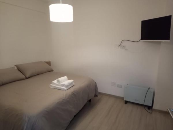 1 dormitorio con 1 cama y TV en la pared en Cabildo Complete Suite 3 en Buenos Aires