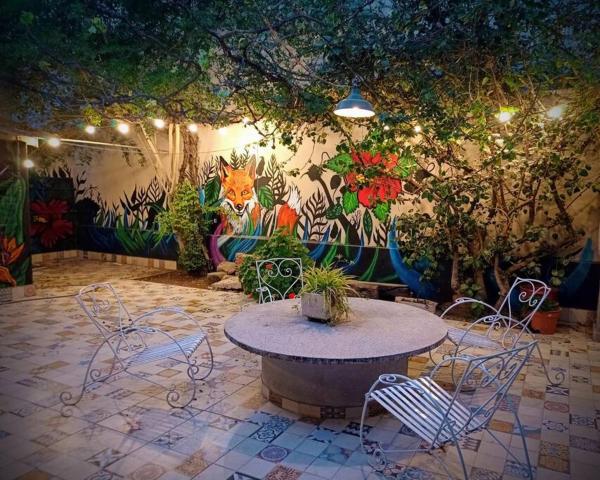 un patio con mesa y sillas frente a un mural en La Casa de la Puerta Azul en Mendoza