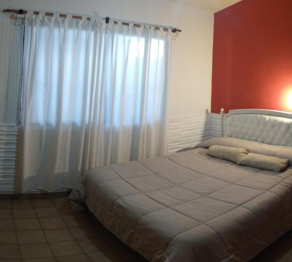 1 dormitorio con 1 cama grande y cortinas blancas en Casa alojamiento Sweet IZABEL en Chascomús