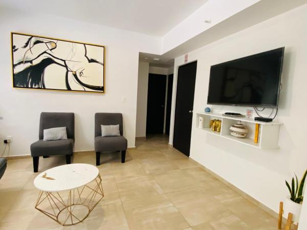 sala de estar con 2 sillas y TV en la pared en Cancun House con lavadero 8-10 personas, en Cancún