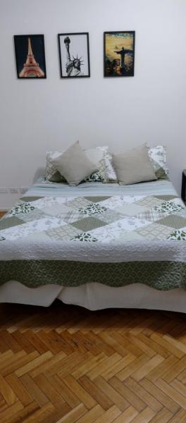 1 cama en un dormitorio con cuadros en la pared en Departamento en Congreso en Buenos Aires