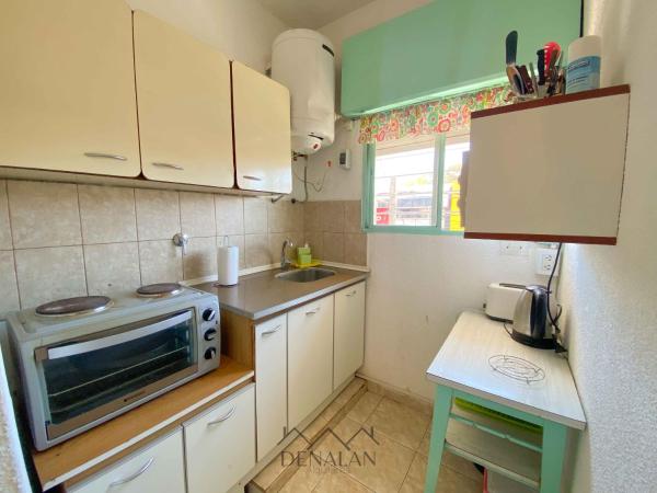 una pequeña cocina con armarios blancos y microondas en el Departamento Denalan en Villa Gesell