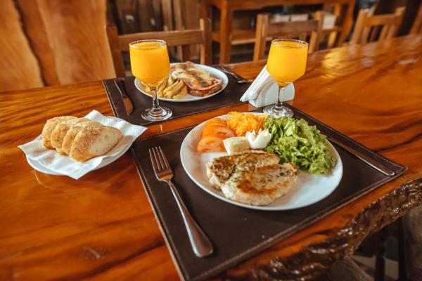 una mesa con dos platos de comida y dos vasos de zumo de naranja en Palo Rosa Lodge en Puerto Iguazú