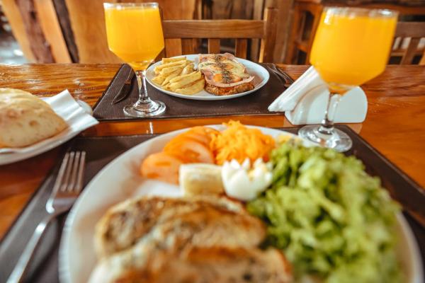 una mesa con un plato de comida y dos vasos de zumo de naranja en Palo Rosa Lodge en Puerto Iguazú