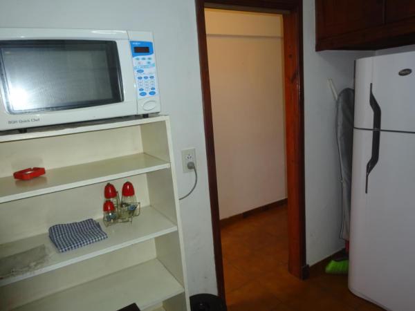 un microondas en la parte superior de un estante junto a una heladera en Veranogesell en Villa Gesell