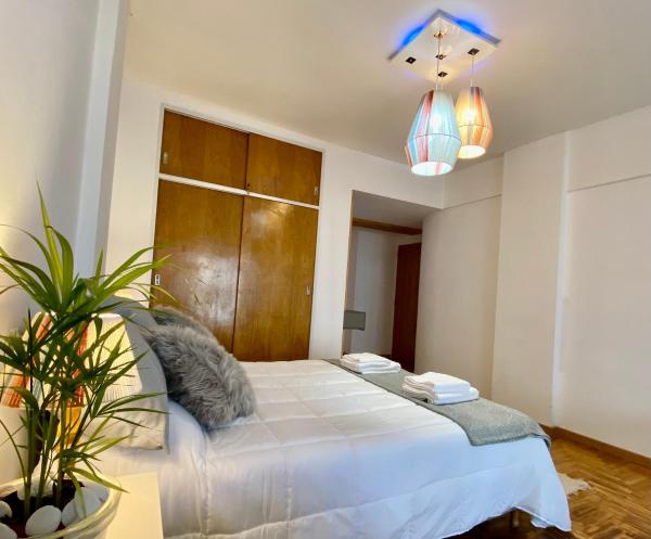 1 dormitorio con 1 cama blanca grande y 2 luces en Monoambiente de diseño confortable -Puerto Madryn en Puerto Madryn