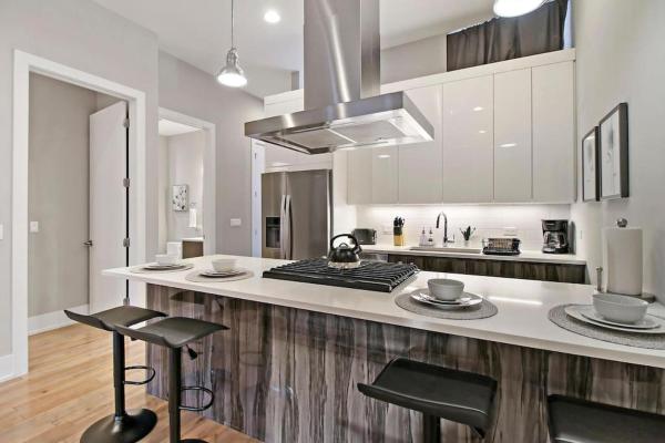 una cocina con armarios blancos y una barra con taburetes en 2BR Well-Equipped Apartment with Laundry and Wi-Fi - Crosby 205, en Chicago