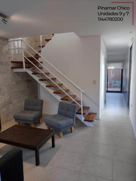 Una escalera en una habitación con 2 sillas y una mesa en Pinamar - Duplex excepcional con pileta en Pinamar