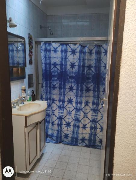 baño con cortina de ducha azul y lavamanos en Casa al fondo en Mar del Plata