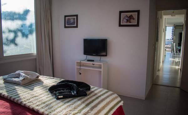 1 dormitorio con 1 cama y TV en la pared en Maitenas VIP en Pinamar
