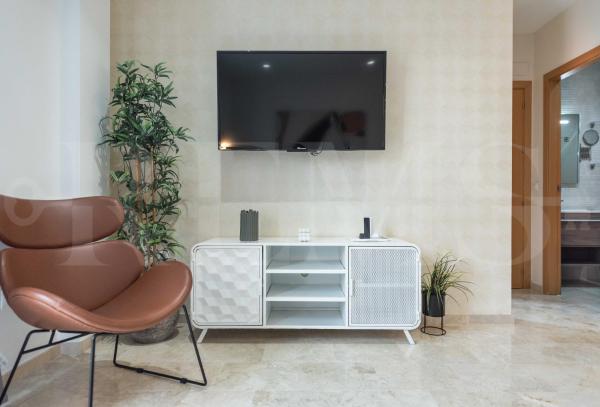 sala de estar con silla y TV en la pared en Lovely duplex with private parking near city center, en Málaga