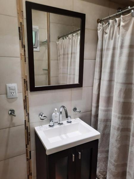 y baño con lavabo, espejo y ducha. en Departamento Mendoza en Mendoza