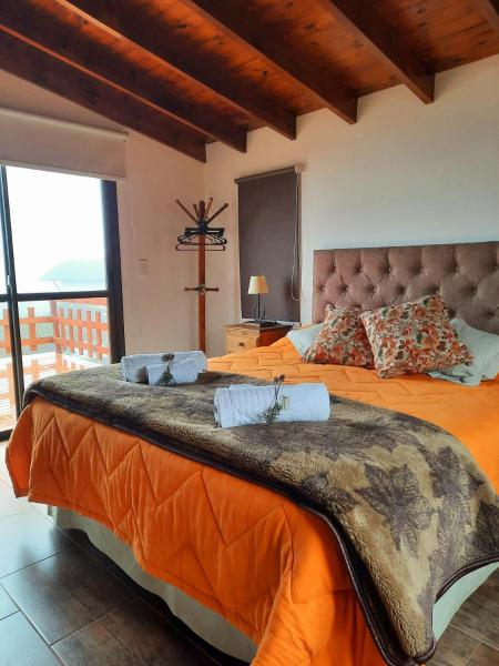 1 dormitorio con 2 camas con sábanas de color naranja en MiraSierras -casas vacacionales- en Villa General Belgrano