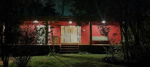 una casa roja con una puerta blanca en la noche en OMA CHILL HOUSE IGUAZU en Puerto Iguazú