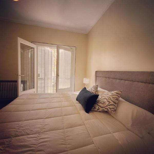 1 dormitorio con 1 cama grande con almohadas y ventana en La Rufina B&B en Mendoza