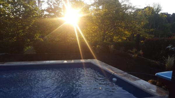una piscina con el sol en el fondo en CasasierraMDQ Lugar de encanto para descansar en Sierra de los Padres