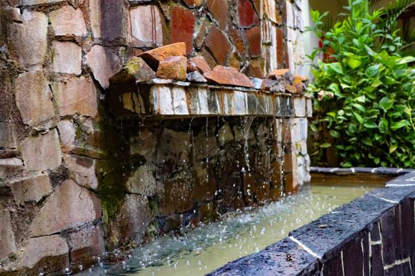 una fuente de agua al lado de un edificio de ladrillo en Hotel Jardin De Iguazu en Puerto Iguazú