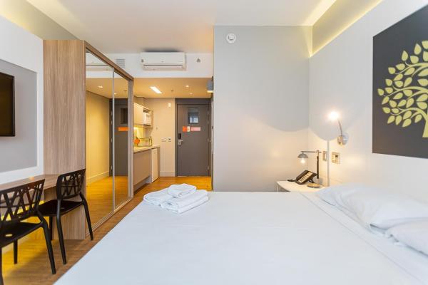 a bedroom with a large white bed and a dining room at Studio Premium Batel - HSB002 in Curitiba