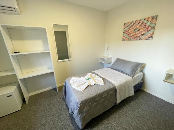 un pequeño dormitorio con una cama y un espejo en Aguila Blanca en Villa Gesell