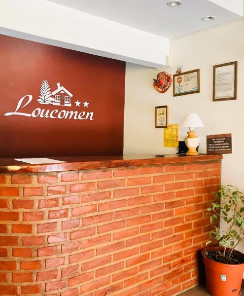 una pared de ladrillo con un letrero de un restaurante en la Hostería Loucomen de Villa Gesell