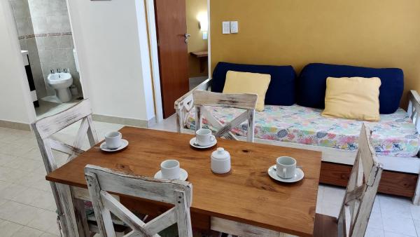 una mesa y sillas con un sofá en una sala de estar en Apart Octogono Condominio en Villa Gesell