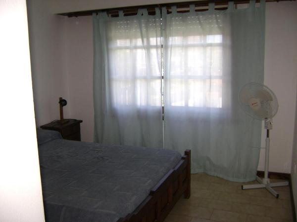 un dormitorio con una cama y una ventana con ventilador en El Ebro en Villa Gesell
