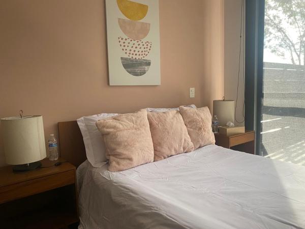 Una cama con sábanas blancas y almohadas en un dormitorio en ACOGEDOR DEPARTAMENTO en zona de Santa Fé, en Ciudad de México