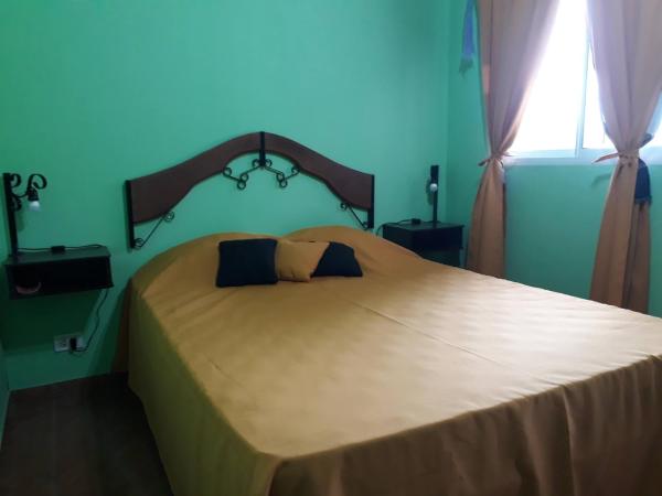 1 dormitorio con 1 cama grande y pared azul en Cabañas Dulce Atardecer, en Villa Carlos Paz