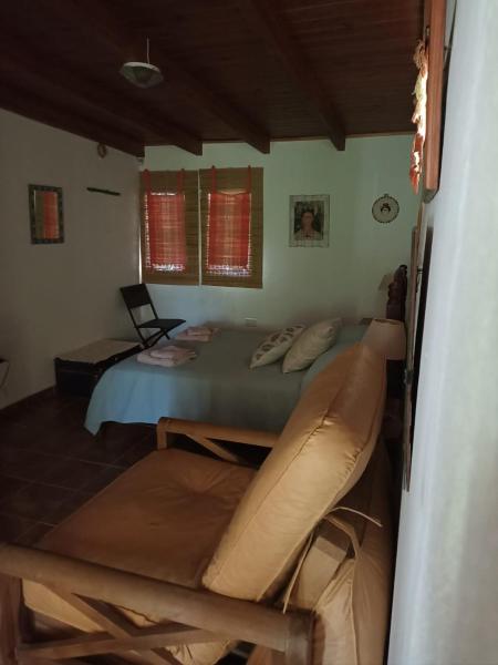 1 dormitorio con cama y sofá en Cabañas Farah Estancia Vieja ideal para 2, en Villa Carlos Paz