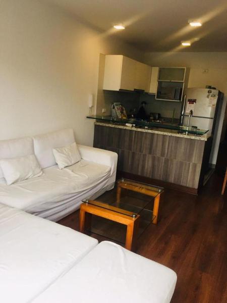 sala de estar con 2 sofás blancos y cocina en Edificio Boem - Barranco, en Lima