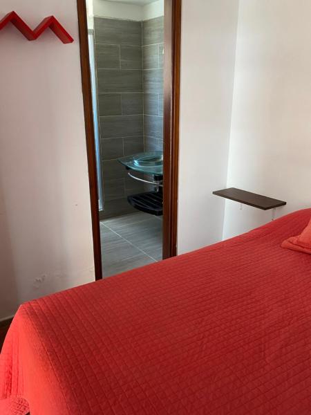 1 dormitorio con cama roja y ducha a ras de suelo en Apartamento a pasos del mar de Playa Brava, en Punta del Este