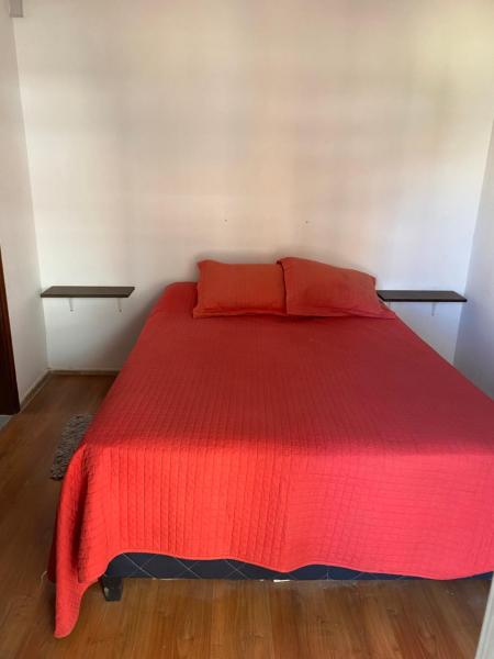 1 cama roja con 2 almohadas rojas en una habitación en Apartamento a pasos del mar de Playa Brava, en Punta del Este