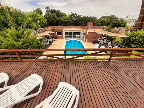 una terraza con sillas blancas y una piscina en Rincon del Sol en Villa Gesell
