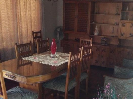 una mesa de comedor con sillas y un jarrón rojo. en Grali home en Mendoza