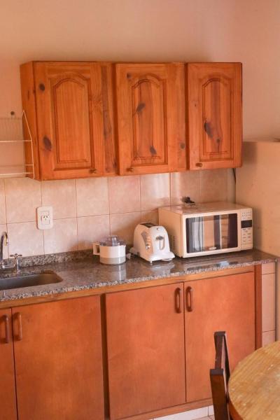 una cocina con armarios de madera y un microondas en el mostrador de Laberinto Gesell en Villa Gesell