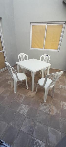 una mesa y sillas blancas en una habitación con ventana en Departamento La Tercera en San Clemente del Tuyú