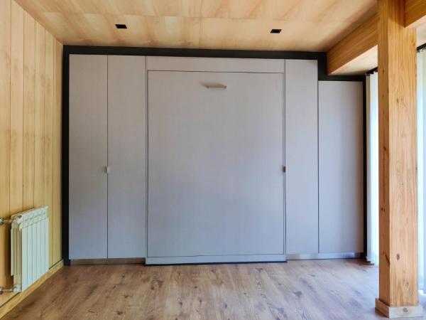 Habitación con suelo de madera y armario con puertas blancas. en Departamento dos ambientes, muy cálido y luminoso, en el centro de SMA. 17V5 en San Martín de los Andes
