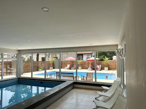 una piscina con 2 sillas blancas y una piscina en Suite del sol en Pinamar