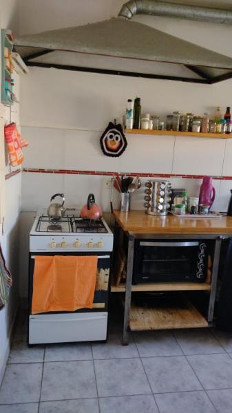cocina con fogones y mesa de madera en Alquilo solo habitación en casa en Puerto Madryn