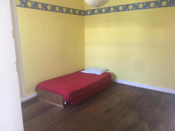 Habitación amarilla con cama con manta roja en Casapuerto, en Valparaíso
