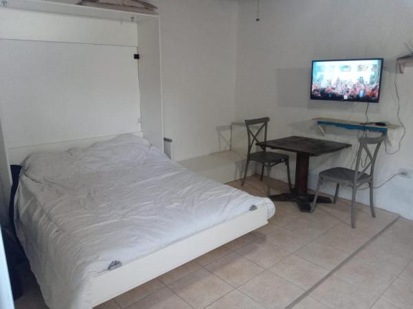 1 dormitorio con cama, mesa y TV en Monoambiente completo con 2 patios y parrilla. en Ostende