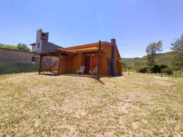 una pequeña casa amarilla con dos sillas en un patio en Vista Bonita en Villa General Belgrano