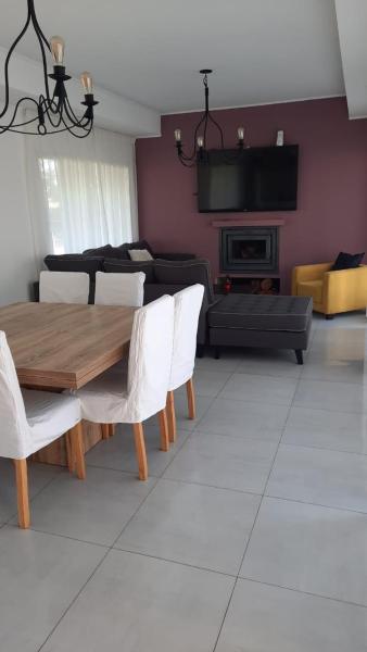 sala de estar con mesa de madera y sillas blancas en La Herradura en Pinamar
