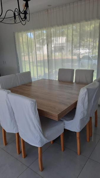 una mesa de comedor de madera con 2 sillas alrededor en La Herradura en Pinamar